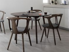 a dining table with four chairs around it in a white room next to a window