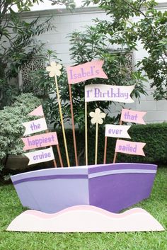 a purple boat with pink and white signs on it's side in the grass