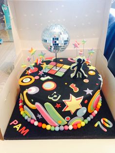 a birthday cake in a box with disco balls and stars on it, as well as a mirror ball