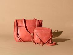 two pink handbags sitting next to each other on a beige background, one has a cross - body bag and the other is a shoulder bag