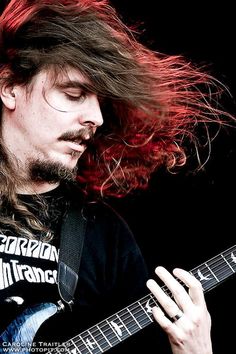 a man with long hair playing an electric guitar