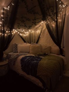 a bedroom with lights strung from the ceiling and curtains on the wall above the bed