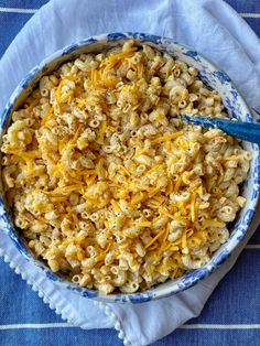 a bowl filled with macaroni and cheese on top of a blue table cloth