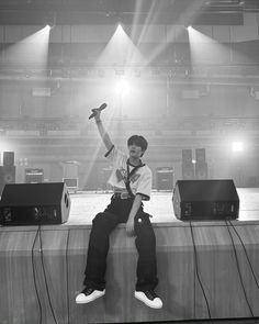 a young man sitting on top of a stage with his hands up in the air