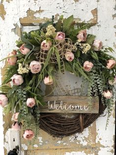 a welcome wreath with pink flowers on an old door