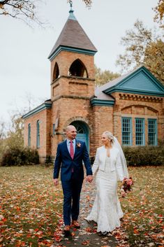 a bride and groom walking in front of an old brick church on their wedding day