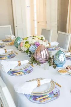 the table is set with plates, silverware and floral centerpieces on it