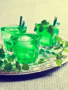 two glasses filled with green drinks on a plate