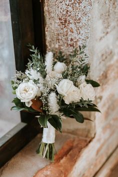 a bouquet of white flowers sitting on top of a window sill