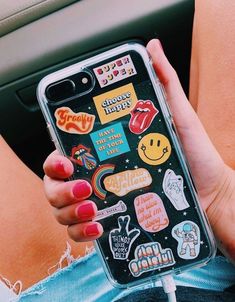 a woman holding an iphone case with stickers on it