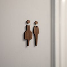 two wooden figures on the side of a white wall next to each other, one with a man and woman's head