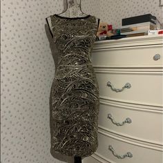 Neck Lined With Sheer Trim Gold Sequins Gold Embroidery Zipper Closure Shell: 100% Nylon Embroidery: 67% Polyester 33% Metallic Lining: 96% Polyester 4% Elastane Fitted Embroidered Dress With Sequins For Party, Elegant Fitted Dress With Gold Embroidery, Elegant Embroidered Dress For Party With Gold Details, Fitted Embroidered Dress For Party, Elegant Fitted Embroidered Dress For Festive Occasions, Elegant Party Dress With Gold Embroidery, Elegant Gold Embroidered Dress For Party, Intricate Embroidery Fitted Party Dress, Knee-length Embellished Embroidered Party Dress