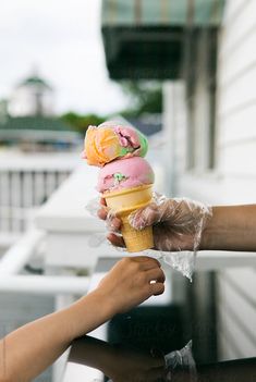 two people holding up ice cream cones on top of a table