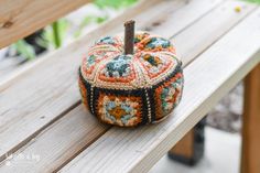 a crocheted pumpkin sitting on top of a wooden bench