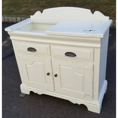 a white cabinet with drawers and doors on the front is sitting in a parking lot