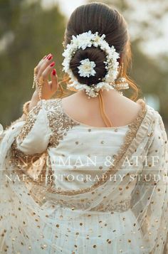 a woman with a flower in her hair wearing a white dress and gold beaded shawl