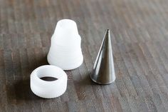 two white plastic cones sitting next to each other on a wooden table with a metal cone