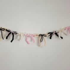 a white and black string with pink bows hanging from it's side on a wall