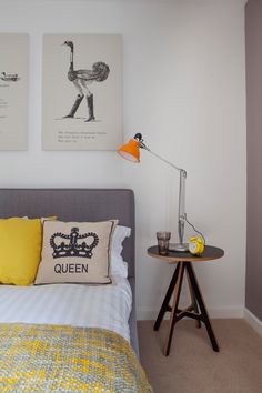 a bed with yellow pillows and two pictures on the wall above it in a bedroom