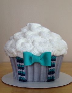 a cupcake decorated with white frosting, blue and green beads and a bow