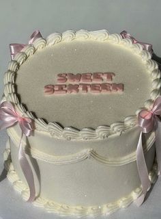 there is a white cake with pink bows on it and the words sweet sixteen written in frosting