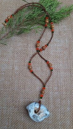 a long necklace with beads and a stone pendant hanging from it's side on a carpeted surface