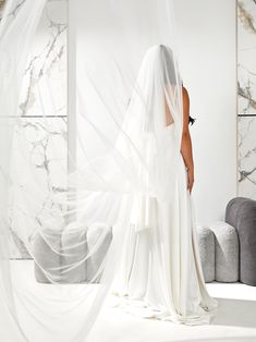 a woman standing in front of a white wall wearing a veil