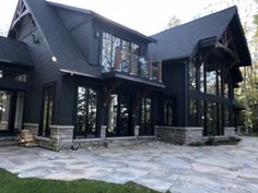 a large black house with lots of windows and stone walkways in front of it