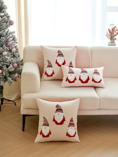 a white couch sitting next to a christmas tree with red and white pillows on it