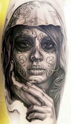 a woman's face painted with black and white sugar skull tattoos on her leg