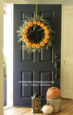 a black door with a wreath and pumpkins on it