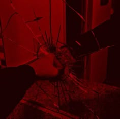 a hand holding a broken glass in front of a red wall