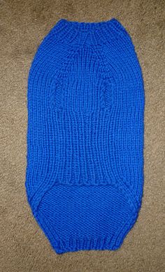 a blue knitted dog sweater laying on the floor