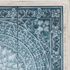 an intricately designed tile with flowers and leaves on the outside, is shown in light blue