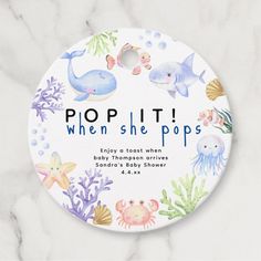 a round button with the words pop it when she pops in front of an image of sea animals