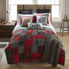 a bed with red and black quilted bedspread in front of a window