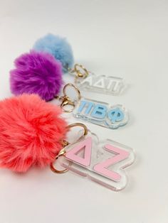 three key chains with fuzzy pom - poms on them