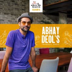 a man sitting on top of a chair in front of a wooden table with an ad for abhay deol's