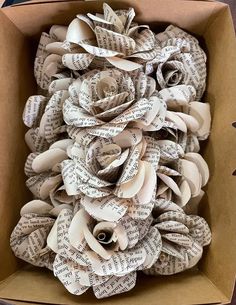 a cardboard box filled with lots of old book pages and paper flowers on top of each other