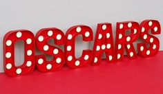 the word oscars spelled with white polka dots on a red surface in front of a gray background