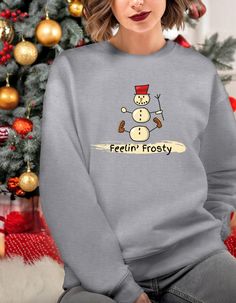 Stay cool and cozy this holiday season with our Feeling Frosty Sweatshirt! Featuring a playful snowman design and a touch of humor, this funny snowman sweatshirt is perfect for adding some frosty fun to your Christmas wardrobe. Whether you're lounging by the fire, heading to a Christmas party, or just embracing the holiday spirit, this sweatshirt is a must-have for the festive season. WELCOME TO RILEY GIRL DESIGNS *This is a unisex heavy blend crewneck sweatshirt  *Material:  50% cotton and 50% polyester *Weight:  (8.0 oz/yd² (271.25 g/m²) *Fit:  Classic - true to size SIZES *See sizing chart in photos. COLORS: *Use drop down menu to view available colors for this item.  See color chart in photos. ---HOW TO ORDER--- 1.Please, check and review all photos 2.Choose your t-shirt size and color Funny Print Long Sleeve T-shirt For Winter, Winter Long Sleeve Tops With Funny Print, Funny Print Long Sleeve Winter Tops, Funny Graphic Print Sweatshirt For Winter, Cotton Tops With Funny Print For Winter, Winter Holiday Relaxed Fit Tops, Funny Cotton Winter Sweatshirt, Winter Holiday Tops With Relaxed Fit, Relaxed Fit Winter Holiday Tops