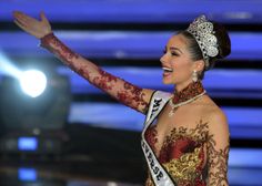 a woman in a red and gold dress waves to the crowd while wearing a tiara