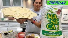 a woman holding a bag of tortillas on top of a counter next to some food