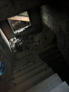 the stairs lead up to an unfinished room with graffiti on it and a blue bottle in the foreground