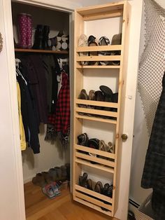 a wooden shoe rack in a closet with shoes on the floor and clothes hanging up