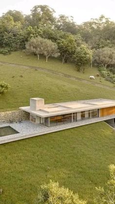 an aerial view of a house in the middle of a grassy field with trees around it