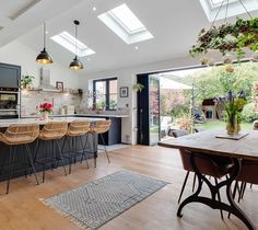 an open kitchen and dining room area with skylights above the countertop, bar stools on either side