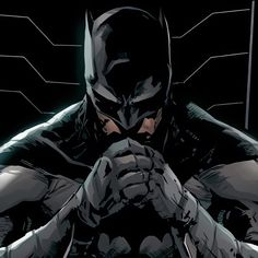 the batman is sitting down with his hands on his face and looking at something in front of him