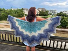 a woman is sitting on a bench with a crocheted shawl draped over her shoulders