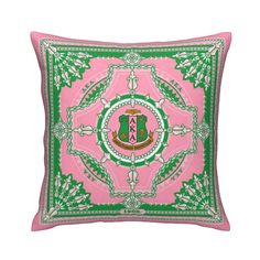 a pink and green pillow with a crest on it